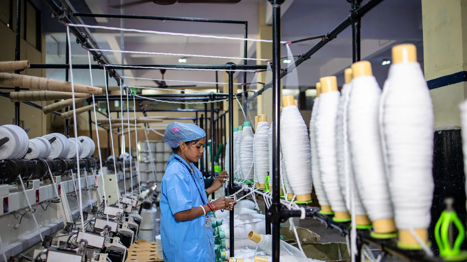 Worker managing yarn winding machines on the floor of an Indian textile manufacturing unit